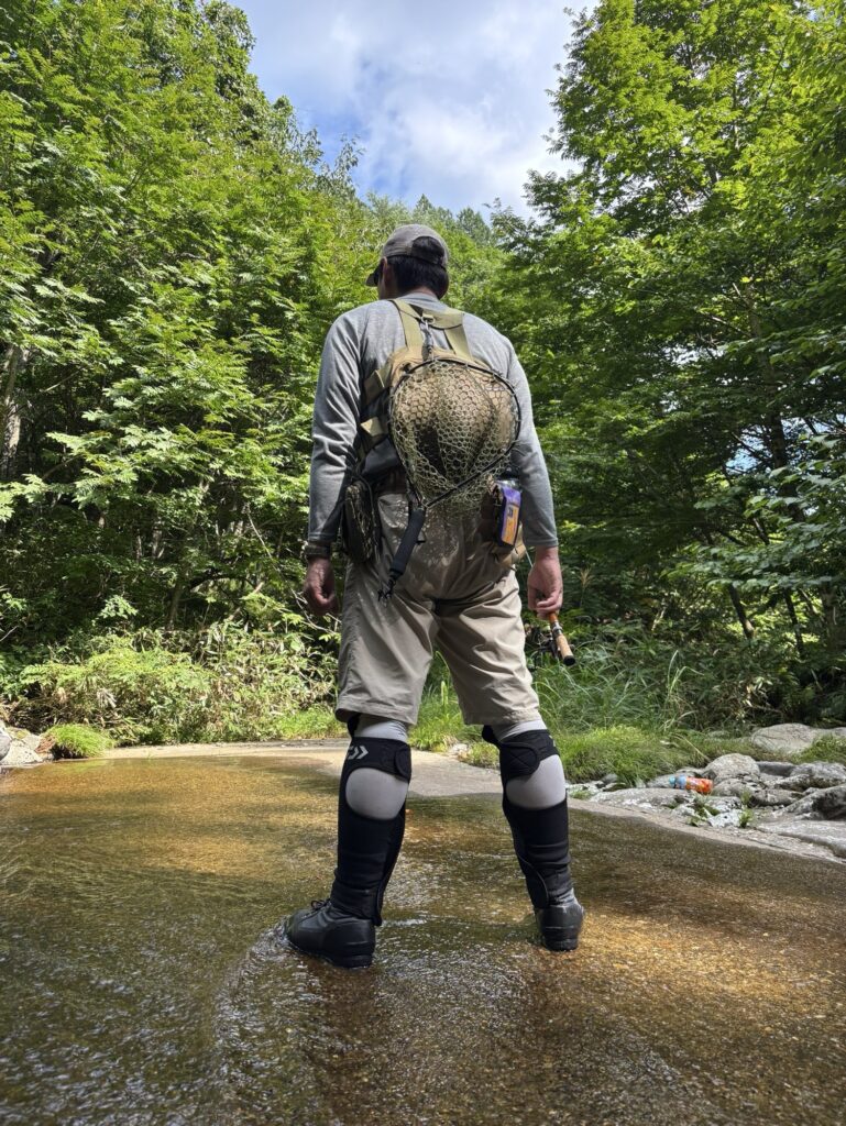 渓流で釣りをする人がシリコンラバーネットを背負っている風景