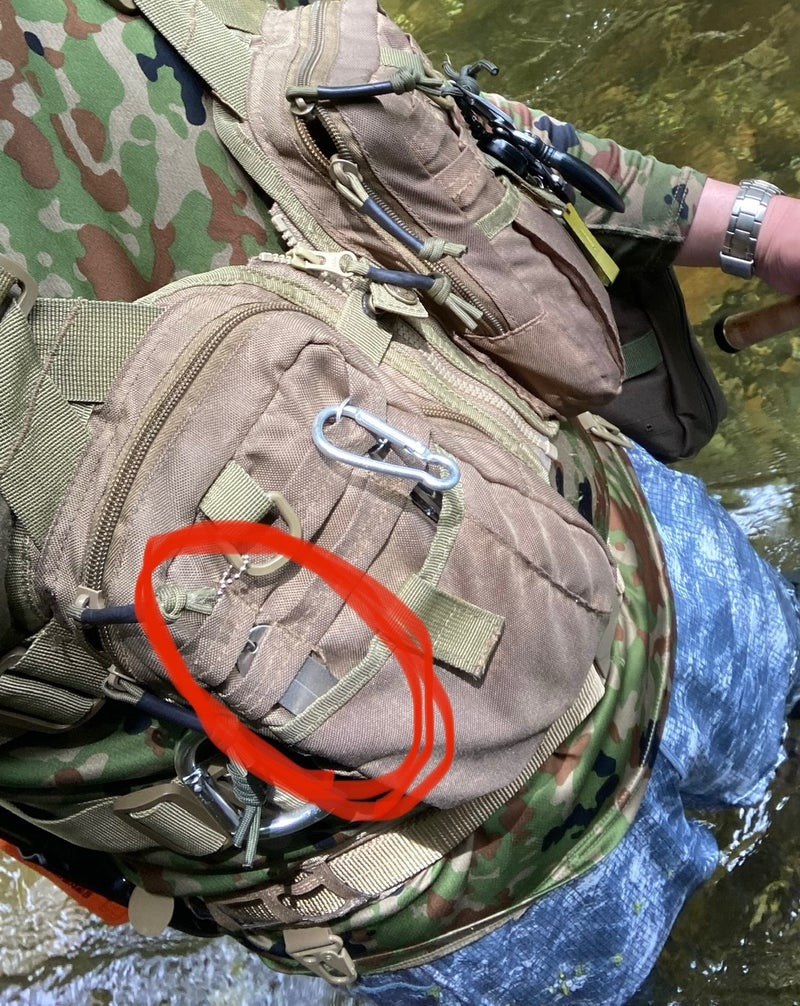 釣り用のウェアに取り付けられたポケットとショルダーハーネスの近接写真。ポケットには傷や摩耗が見られる。