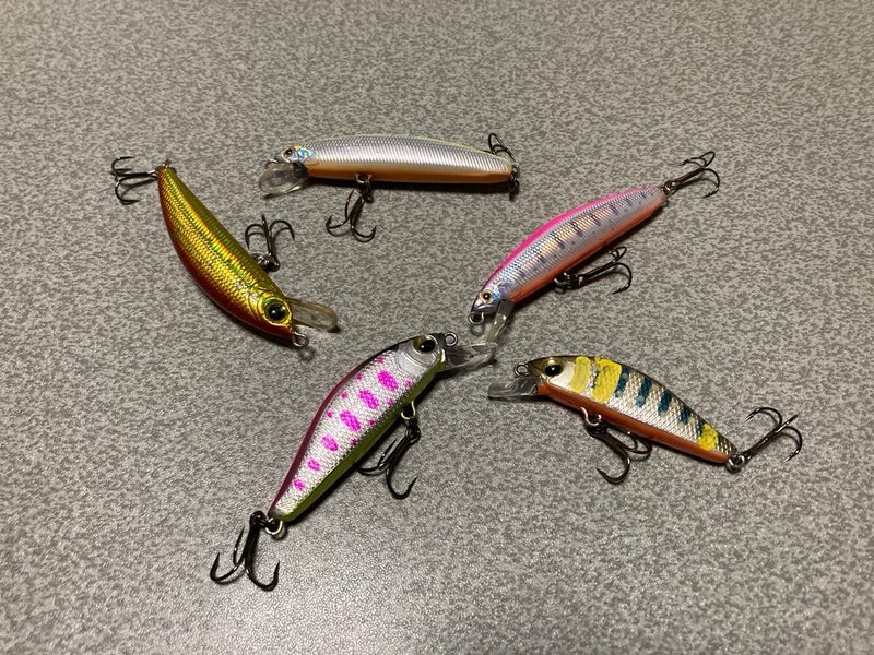 複数のカラフルなルアーが灰色の平面上に配置されている画像