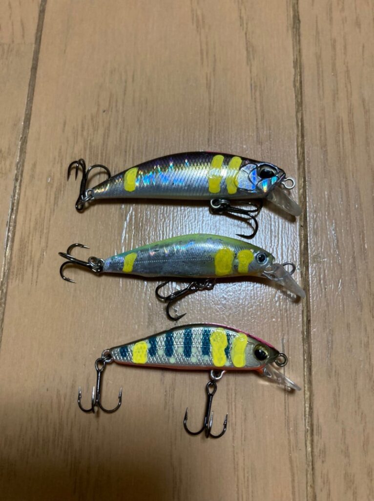 カスタマイズされたルアーが3つ並んでいる画像。異なるサイズとカラーリングのルアーが木製のテーブルの上に置かれている。