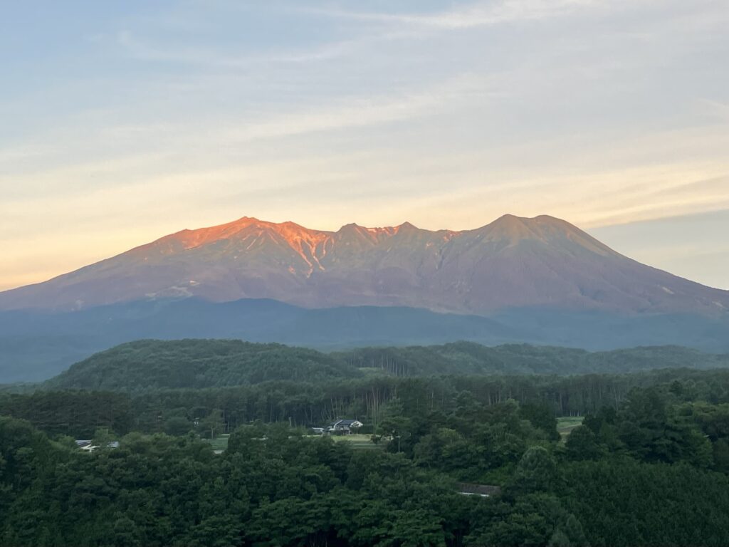 開田高原から望む、朝焼けに映える7月の御嶽山。谷筋には若干の雪が残る。